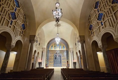 Grand Temple Emanu-El sanctuary with soaring arched ceilings, elegant stained glass, graceful chandeliers, and wooden pews.