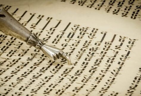 A close-up of a Yad, or Torah pointer, guiding the reading of Hebrew text during the Torah service at Temple Emanu-El, reflecting the reverence and care given to sacred scripture in Jewish tradition.