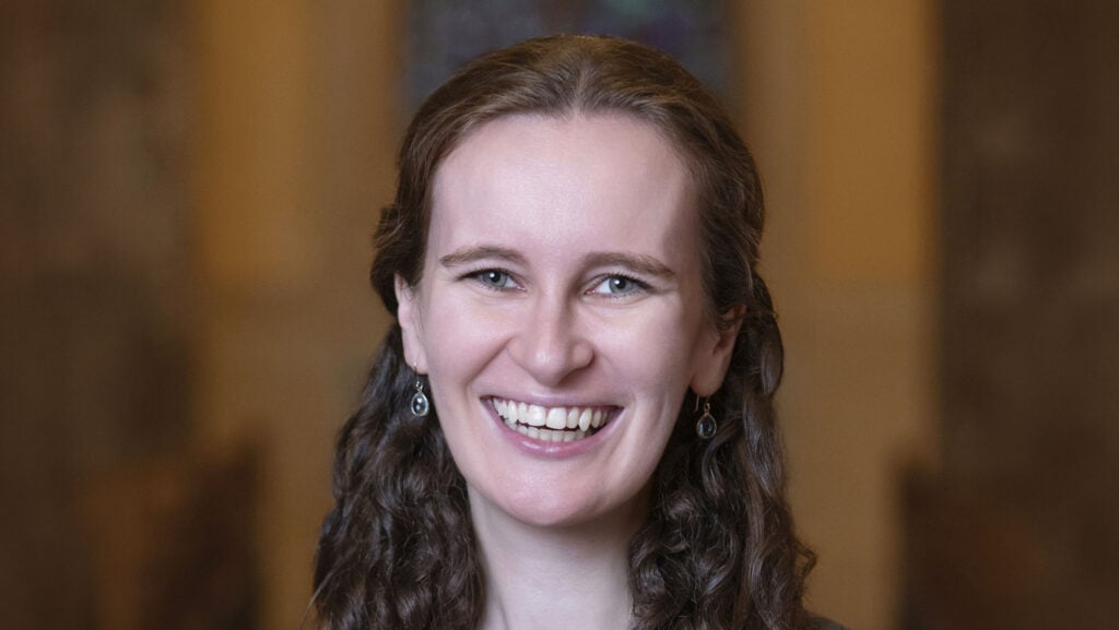 A smiling woman with long brown hair, captured in a portrait at Temple Emanu-El.
