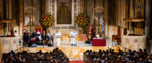 A vibrant community gathering at Temple Emanu-El, featuring musicians and speakers leading a service on the bimah in the synagogue’s grand sanctuary, with congregants seated in attendance.