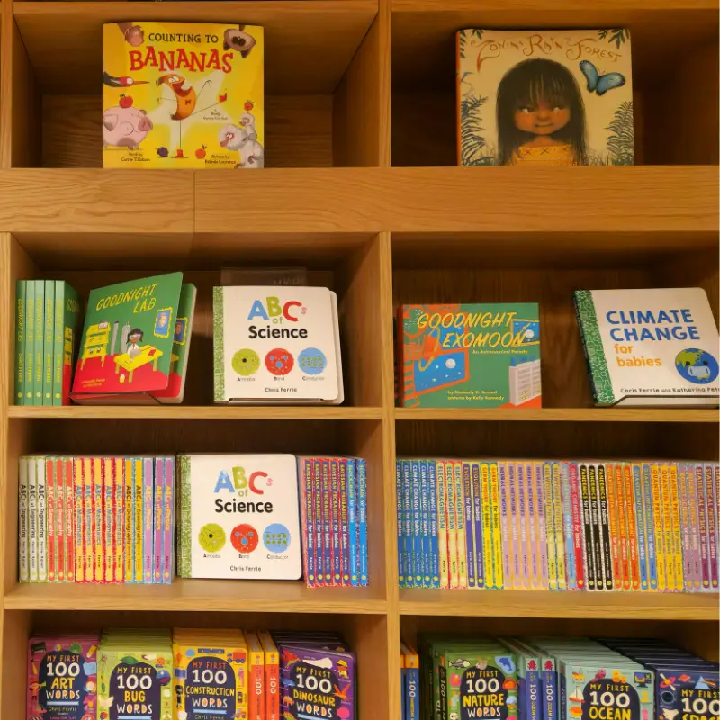 Children’s science and storybooks neatly arranged on wooden bookshelves in the Temple Emanu-El children’s library.