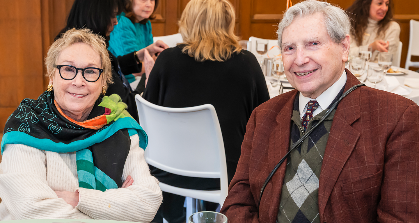 Two smiling temple members sit together at a table during a Temple Emanu-El Community as Family gathering.