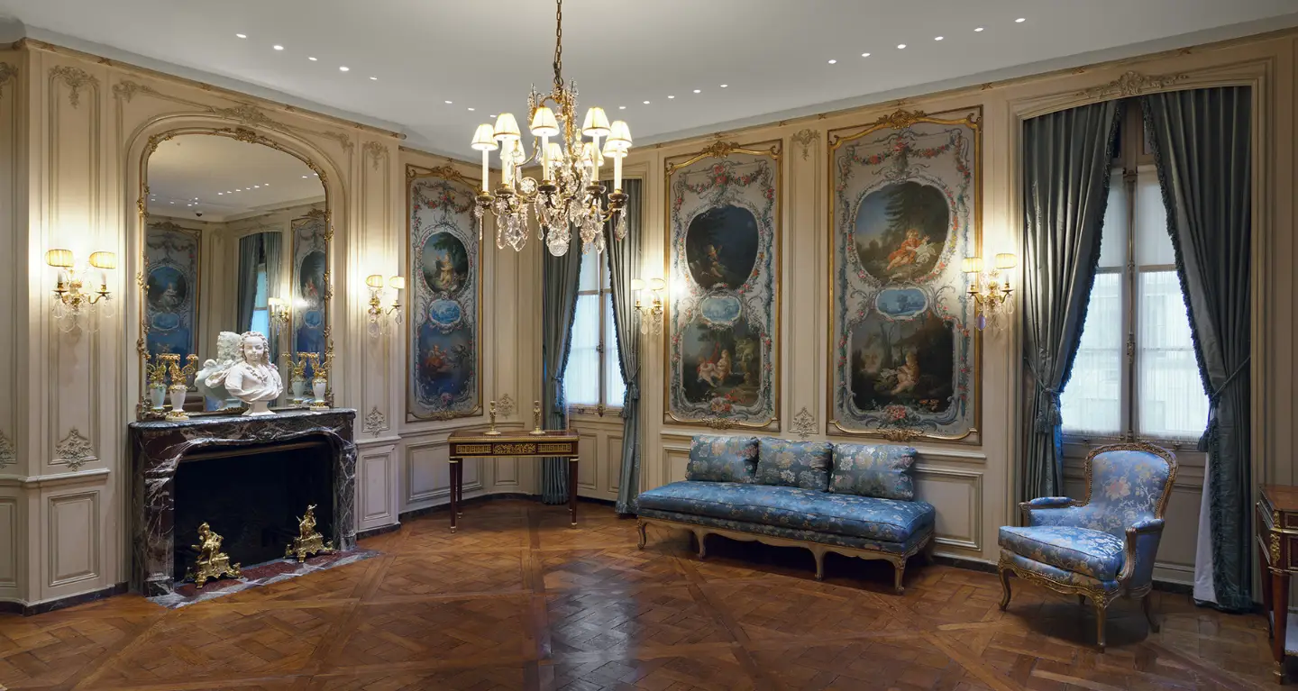 Graceful sanctuary with decorative panels, grand chandelier, marble bimah, blue seating, and parquet flooring.