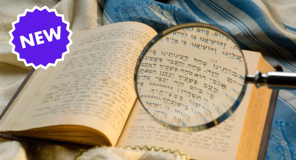 Open Hebrew prayer book with magnifying glass highlighting text, fabric draped nearby, and a purple NEW label in the corner.