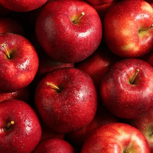 A close arrangement of fresh, glistening red apples, reminiscent of Rosh Hashanah traditions at Temple Emanu-El.