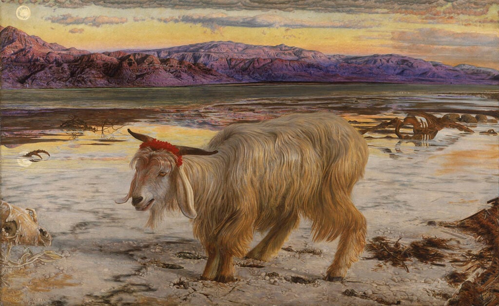A goat with a red cloth on its horns stands against a serene white landscape with distant mountains and water in the background.