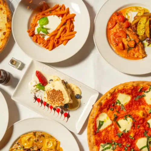 An overhead view of assorted Italian-inspired vegetarian dishes, pastas, and desserts on a white table at a synagogue event.