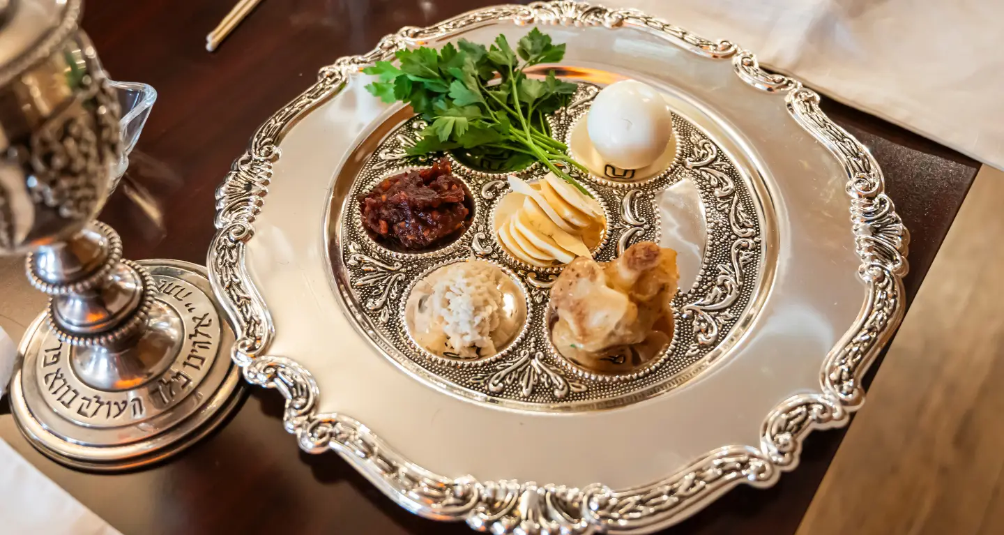 A Passover Seder plate showcasing symbolic foods on an ornate silver tray, prepared for a Reform Jewish celebration at Temple Emanu-El.