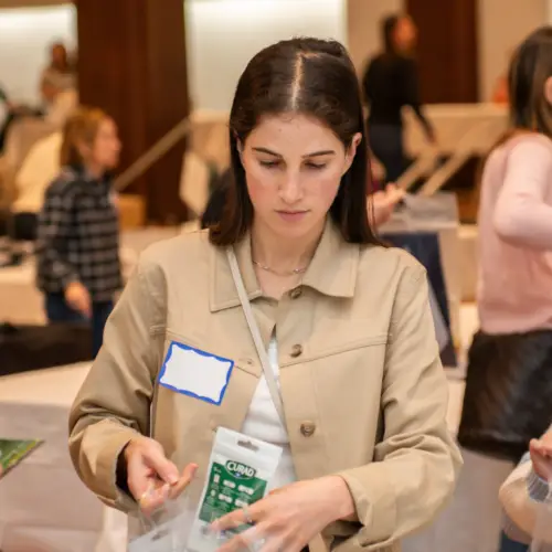 Temple Emanu-El members packing supplies into bags at a community service event, with tables and fellow volunteers in the background.