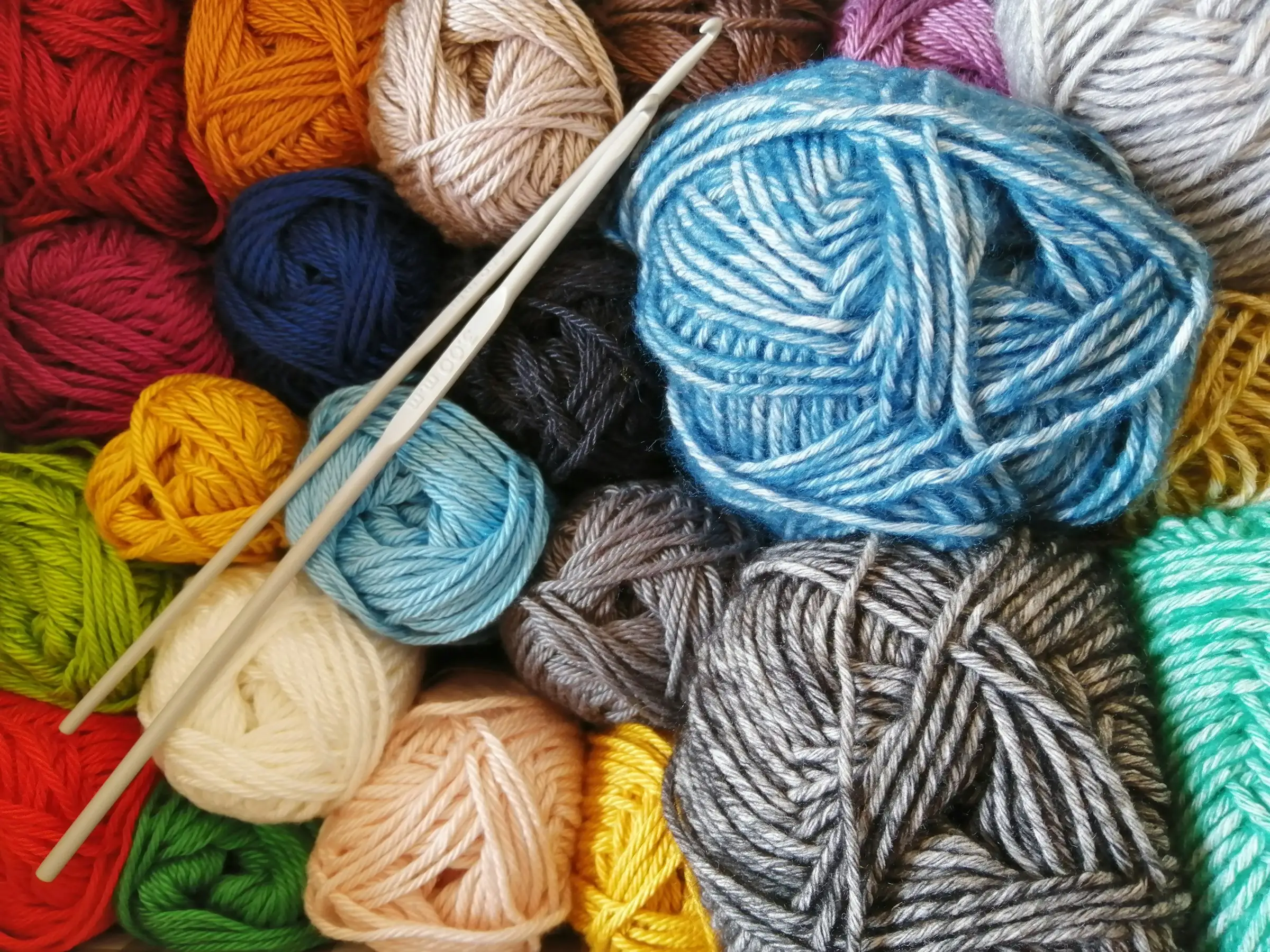 Colorful yarn balls with two knitting needles arranged on top.