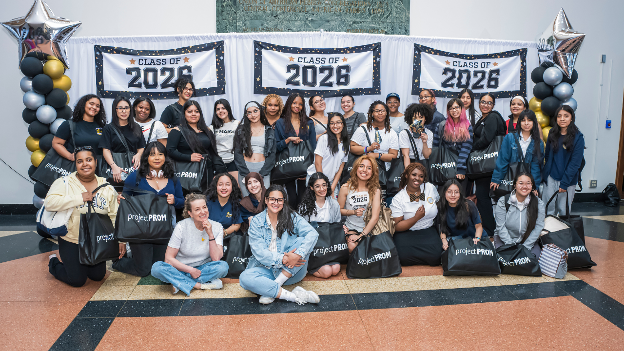New York City High School students participating in Project Prom, smiling in front of “Class of 2026” banners and festive balloons.