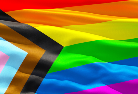 Progress Pride flag featuring rainbow stripes and chevron design on wavy fabric.