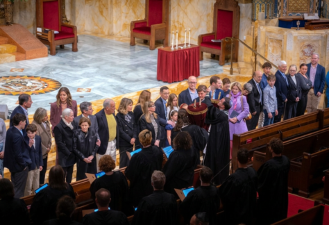 A group of people stands at the front of a sanctuary, facing clergy in robes during a ceremony at Temple Emanu-El.
