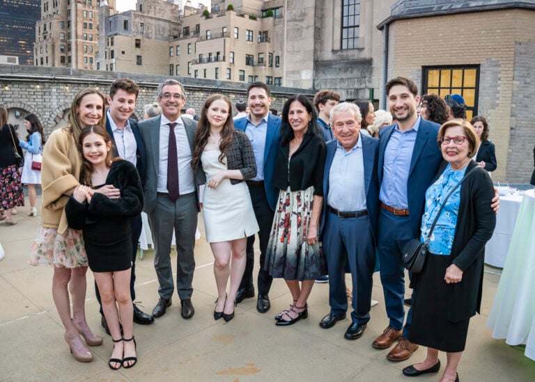 Formally dressed congregants smile together at an outdoor rooftop gathering overlooking the city at Temple Emanu-El.