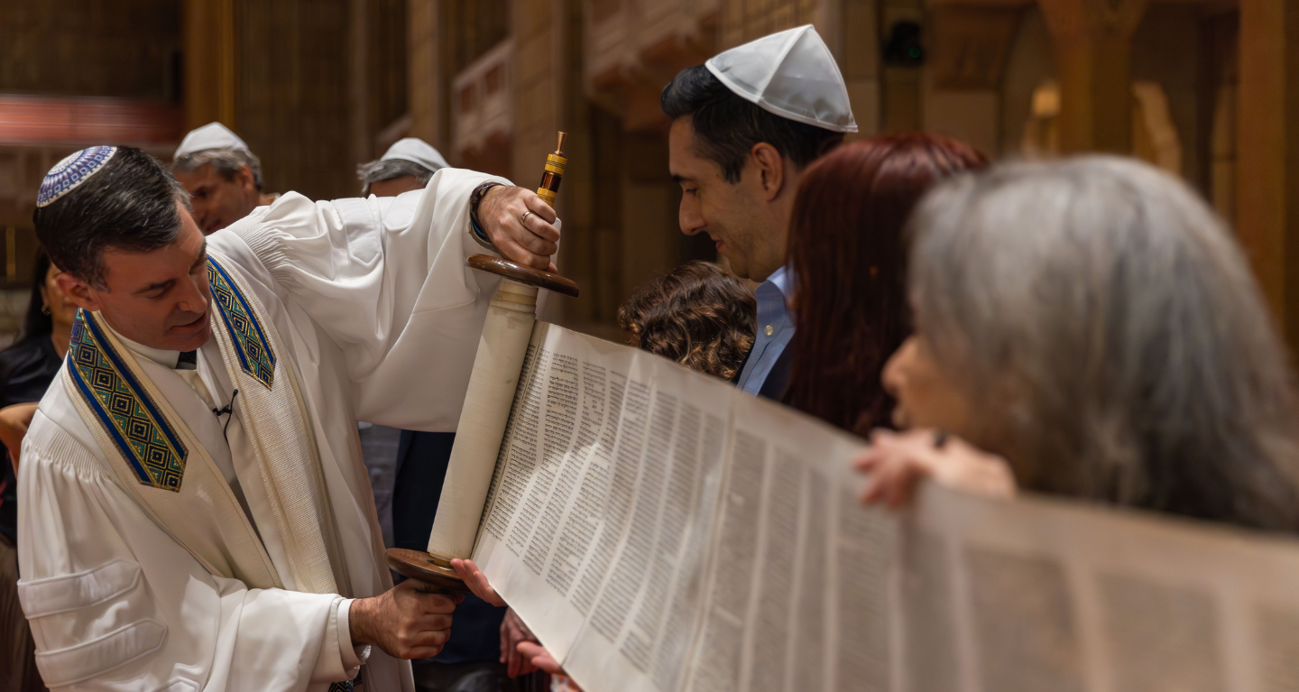 A rabbi at Temple Emanu-El unrolls a Torah scroll with congregants during a Reform Jewish service inside the synagogue’s sanctuary.
