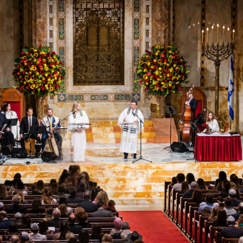 A choir and musicians perform for an audience during a ceremony in the majestic sanctuary of Temple Emanu-El in New York City.
