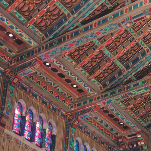 Colorful, intricately patterned ceiling and stained glass windows inside the historic sanctuary of Temple Emanu-El in New York City.