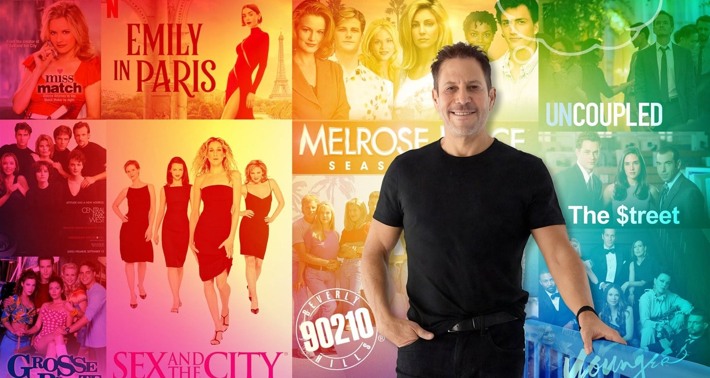 A man stands smiling in front of a vibrant display of posters, set against a colorful, rainbow-gradient background.