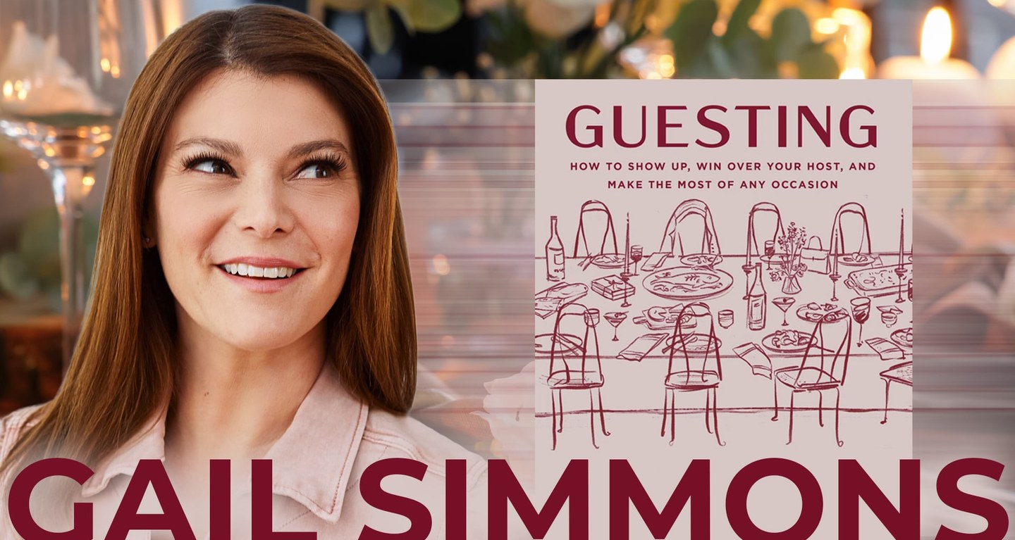 Smiling woman standing next to a book titled “Guesting,” featuring a cover illustration of a dinner table and chairs, photographed at Temple Emanu-El in New York City.