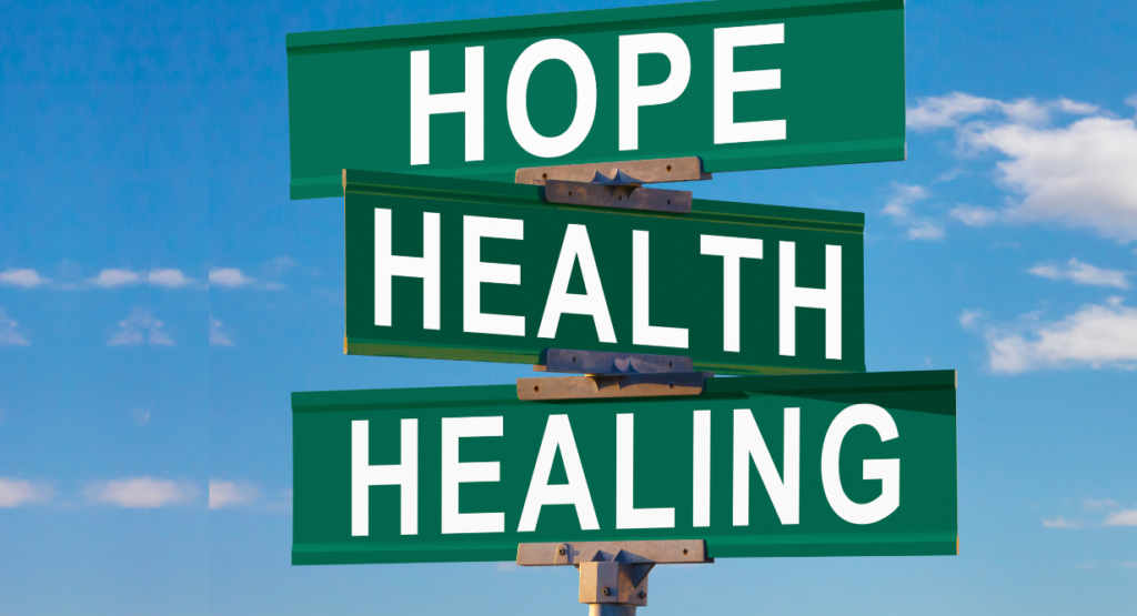 Three green street signs display the words HOPE, HEALTH, HEALING against a blue sky with clouds in the background, reflecting themes of spiritual well-being and community embraced by Temple Emanu-El.