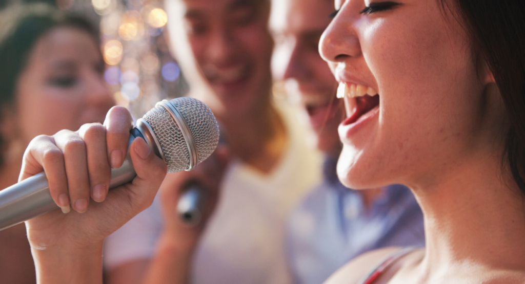 Close-up of a congregant singing into a microphone during a service or event, with fellow community members singing together in the background at Temple Emanu-El.