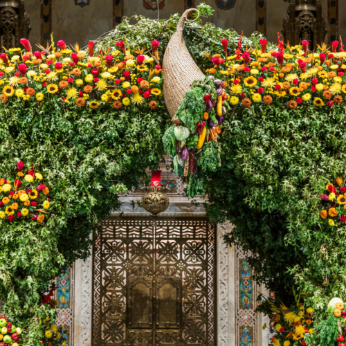 A large floral arrangement featuring green leaves and vibrant yellow and red flowers, with a decorative centerpiece.
