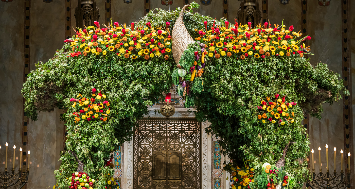 A large floral arrangement featuring green leaves and vibrant yellow and red flowers, with a decorative centerpiece.