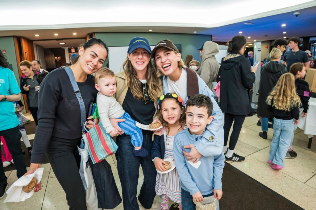A group of parents and children smiling together at a Temple Emanu-El community event.