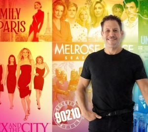 A man stands smiling in front of a vibrant display of posters, set against a colorful, rainbow-gradient background.