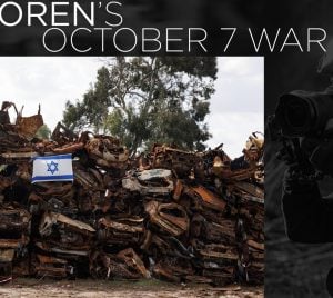 A group of damaged vehicles with an Israeli flag nearby, as a photographer documents the scene on the right side.