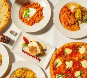An overhead view of assorted Italian-inspired vegetarian dishes, pastas, and desserts on a white table at a synagogue event.