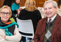 Two smiling temple members sit together at a table during a Temple Emanu-El Community as Family gathering.