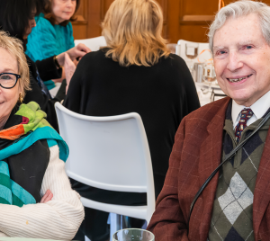 Two smiling temple members sit together at a table during a Temple Emanu-El Community as Family gathering.