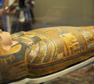 An intricately decorated ancient Egyptian sarcophagus exhibited in a respectful and educational setting.