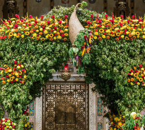 A large floral arrangement featuring green leaves and vibrant yellow and red flowers, with a decorative centerpiece.