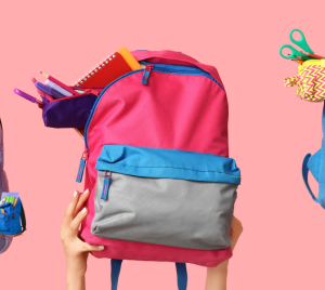 Three colorful backpacks held by hands, filled with school supplies, against a pink background, representing support for students through Temple Emanu-El’s community initiatives.