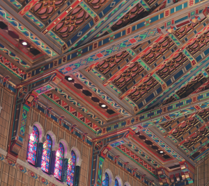 Colorful, intricately patterned ceiling and stained glass windows inside the historic sanctuary of Temple Emanu-El in New York City.