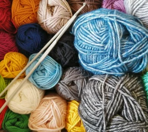 Colorful yarn balls with two knitting needles arranged on top.